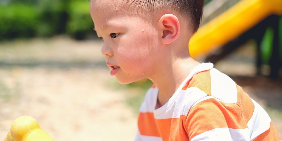 Small boy at a playground on a hot day.