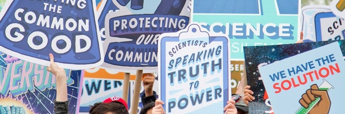 Smiling people with signs marching in support of science.