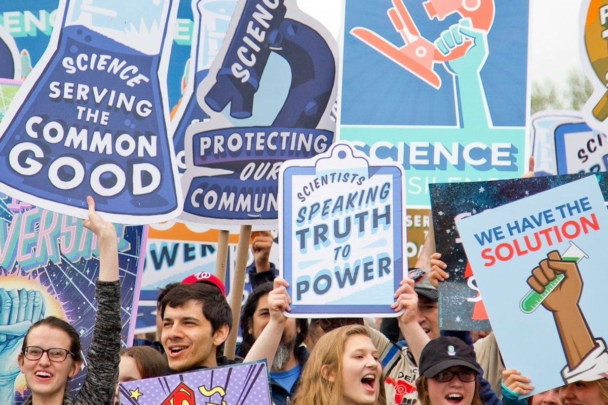 Smiling people with signs marching in support of science.