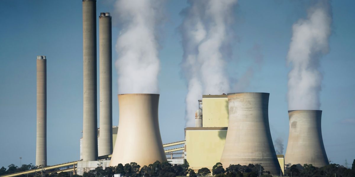 smoke billows from the cooling towers of a power plant.