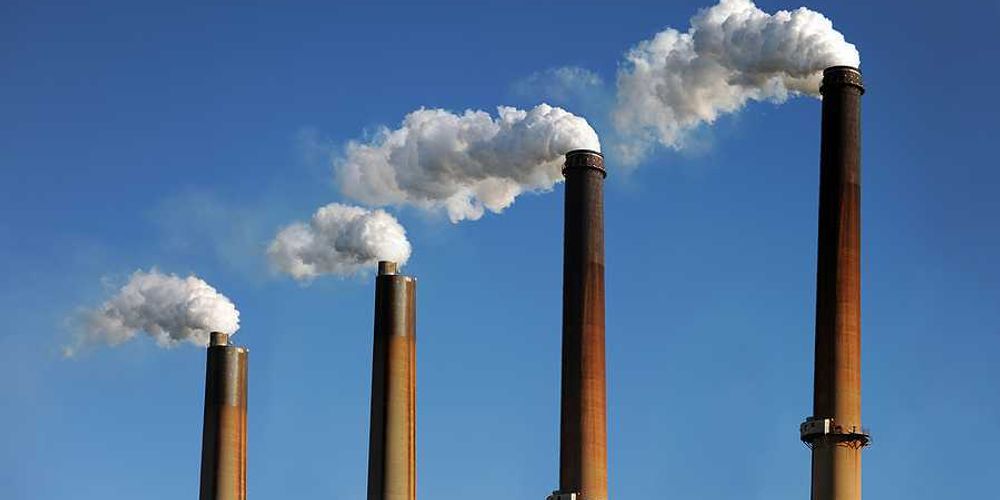 Smokestacks emitting smoke against a blue sky