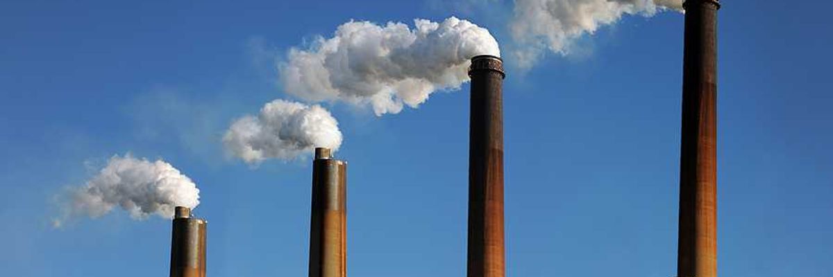 Smokestacks emitting smoke against a blue sky