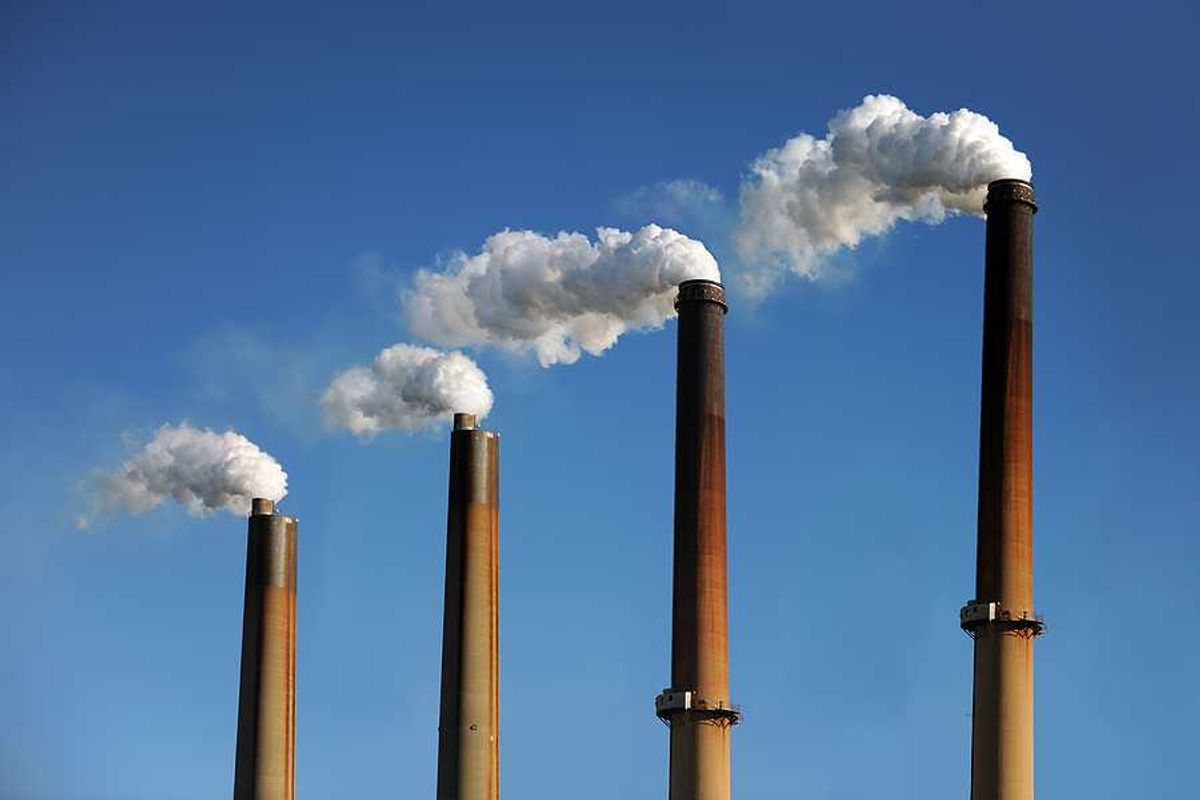 Smokestacks emitting smoke against a blue sky