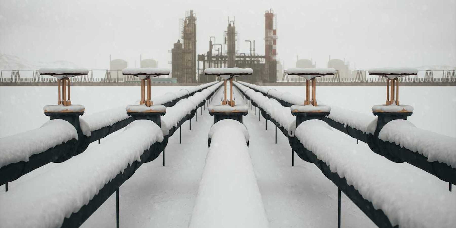 Snow-covered fossil fuel pipeline leading to a refinery.