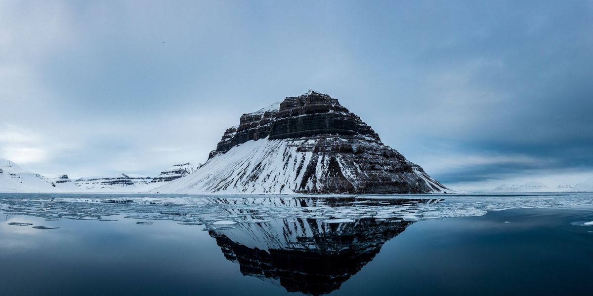 Snow covered mountain near body of water.