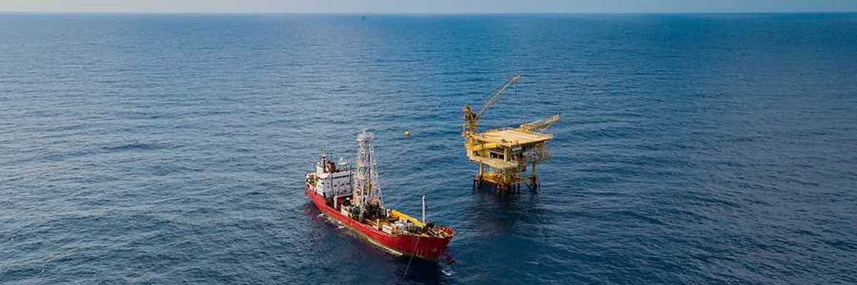Soil Boring Boat aka survey vessel close to an oil platform in open ocean.