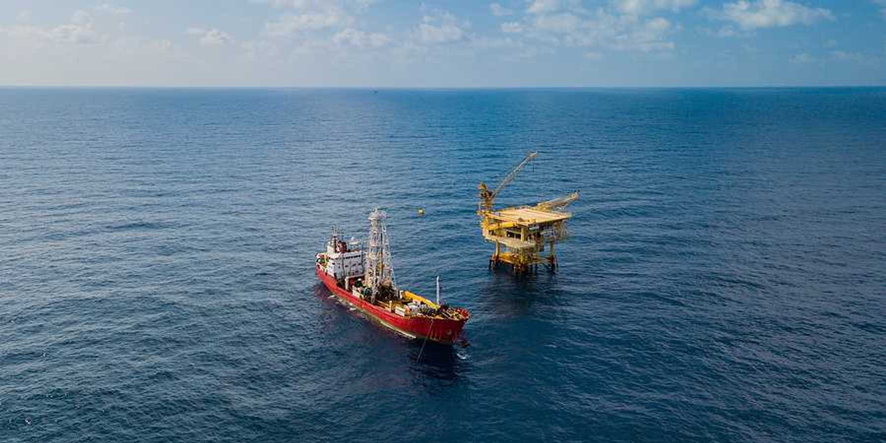 Soil Boring Boat aka survey vessel close to an oil platform in open ocean.