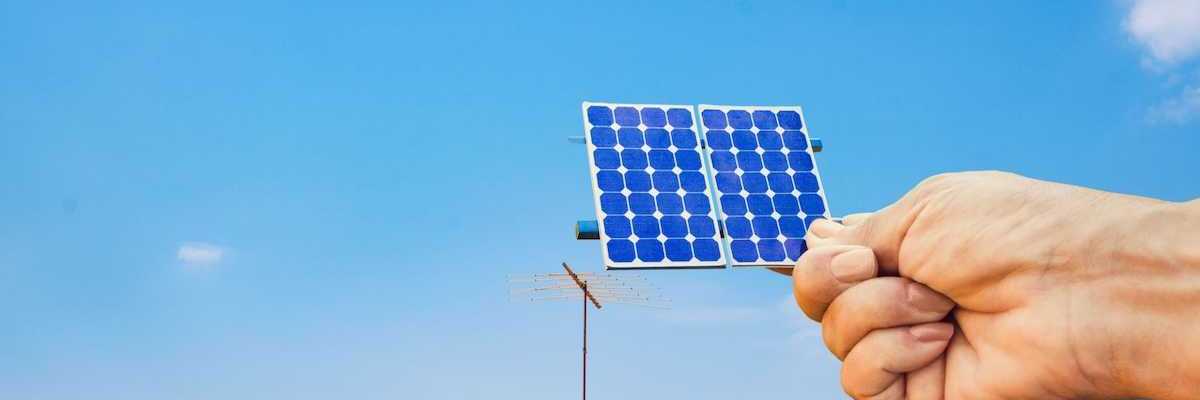 Solar energy panel shown with a hand holding a photovoltaic cell,