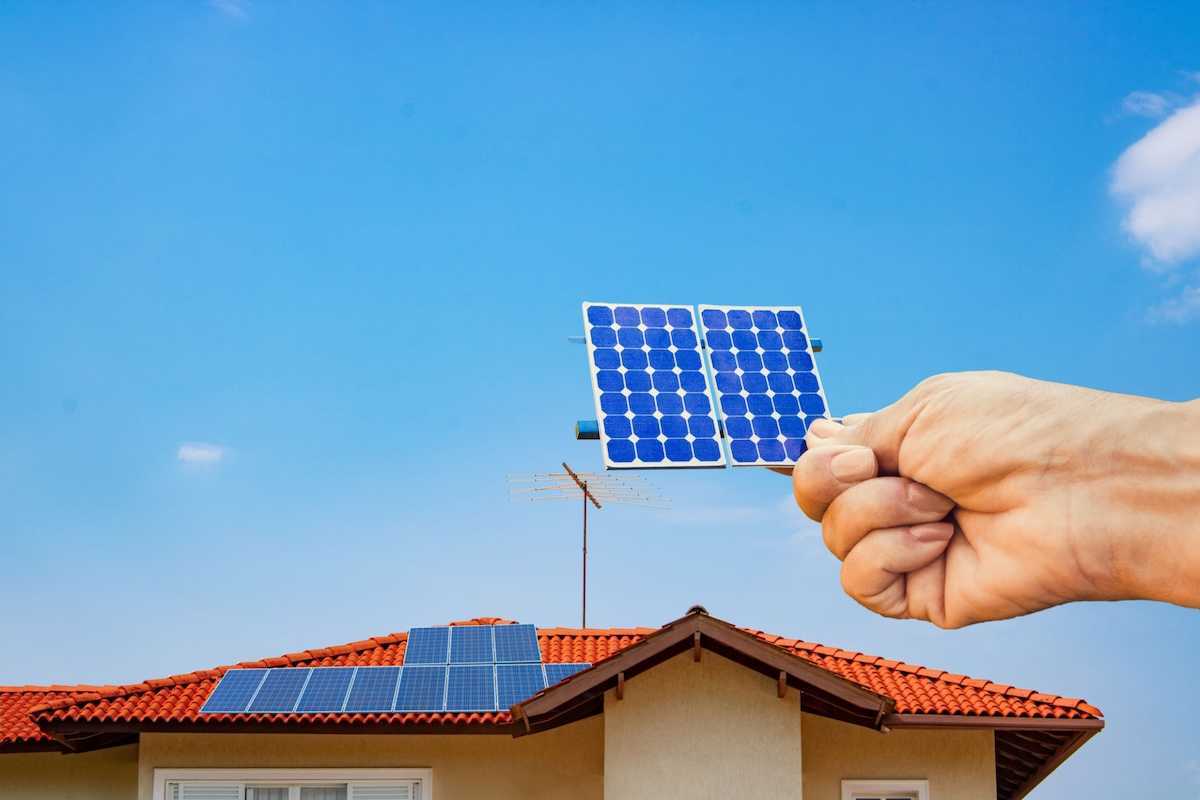 Solar energy panel shown with a hand holding a photovoltaic cell,