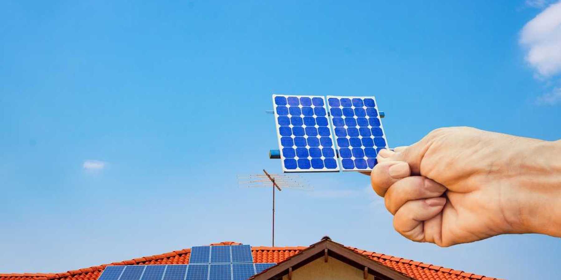 Solar energy panel shown with a hand holding a photovoltaic cell,