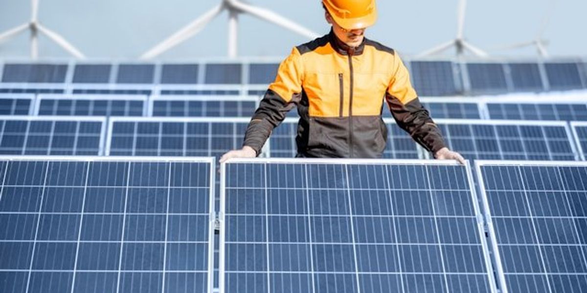 Solar installer with wind turbines in the background.