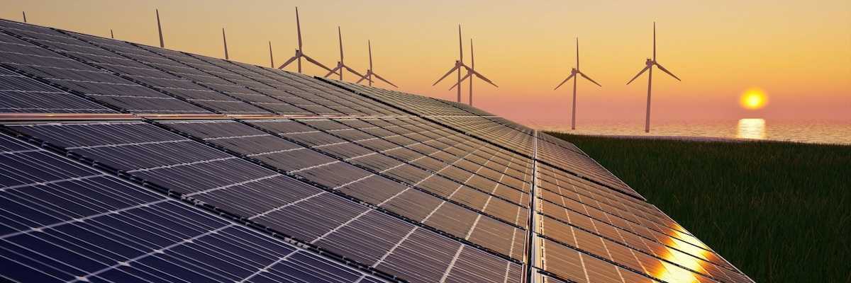 Solar panels and wind turbines against setting sun