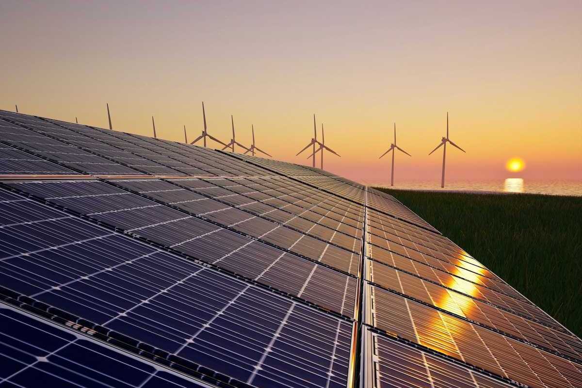 Solar panels and wind turbines against setting sun
