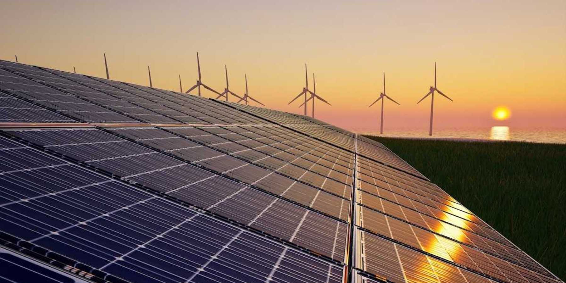 Solar panels and wind turbines against setting sun