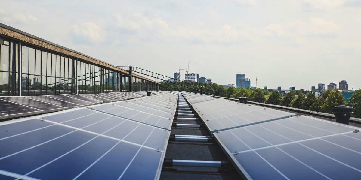 Solar panels extending into the distance on a roof with a city skyline in the background.