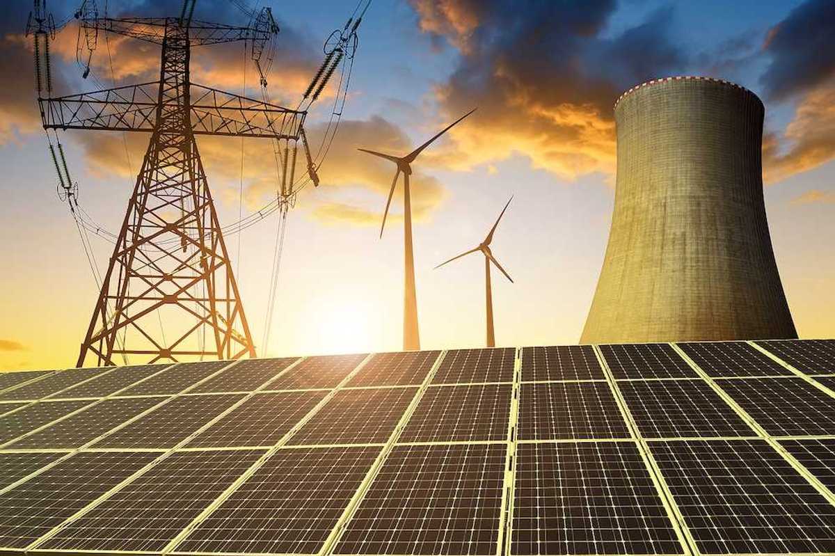 Solar panels in the background nuclear power plant, wind turbines and electricity pylon at sunset.