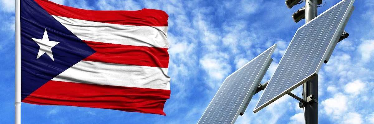Solar panels on a background of blue sky with a flagpole and the flag of Puerto Rico