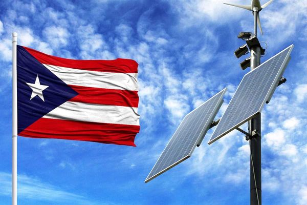 Solar panels on a background of blue sky with a flagpole and the flag of Puerto Rico