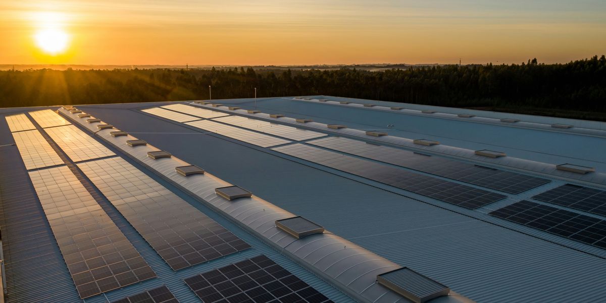 Solar panels on a commercial building rooftop with the setting sun in the background
