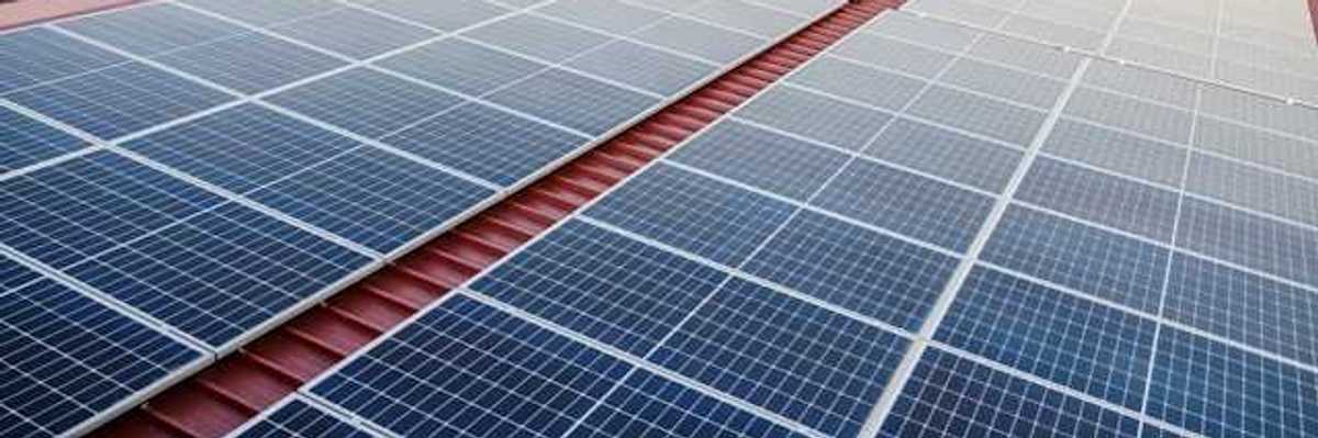 Solar panels on a red metal roof with a green landscape in the background