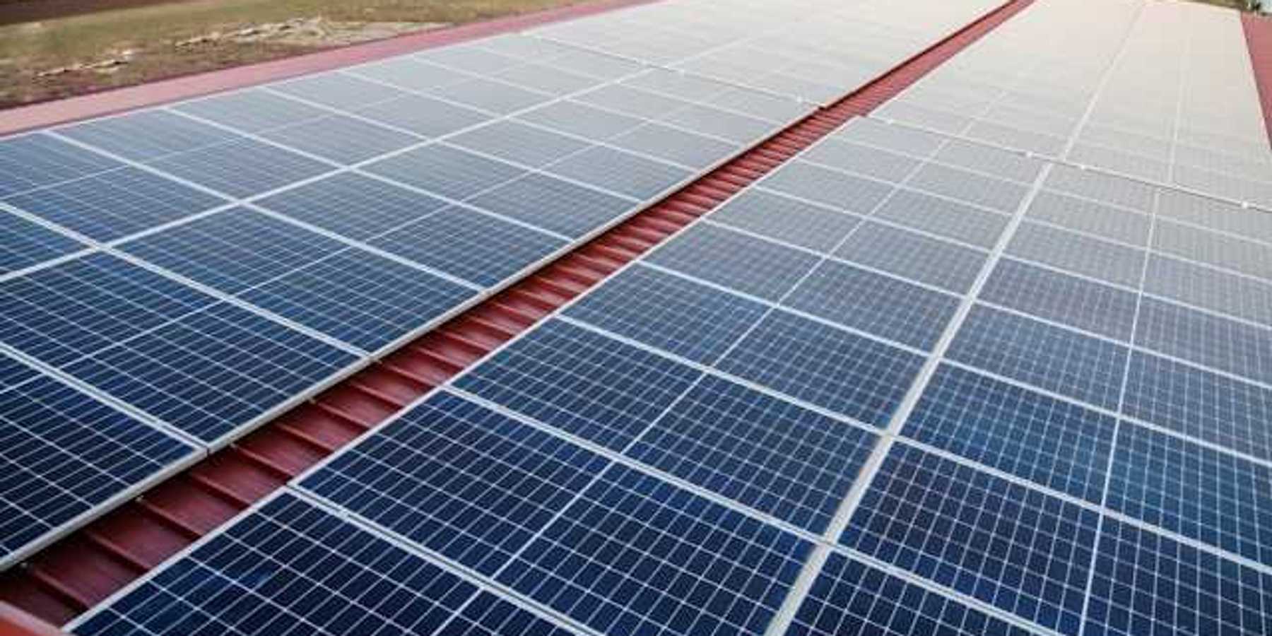 Solar panels on a red metal roof with a green landscape in the background