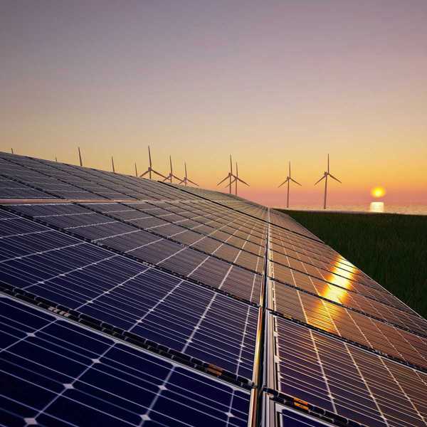 Solar panels & wind turbines against setting sun