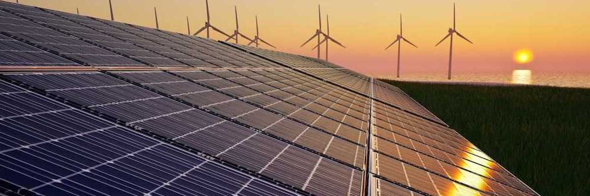 Solar panels with wind turbines in the background