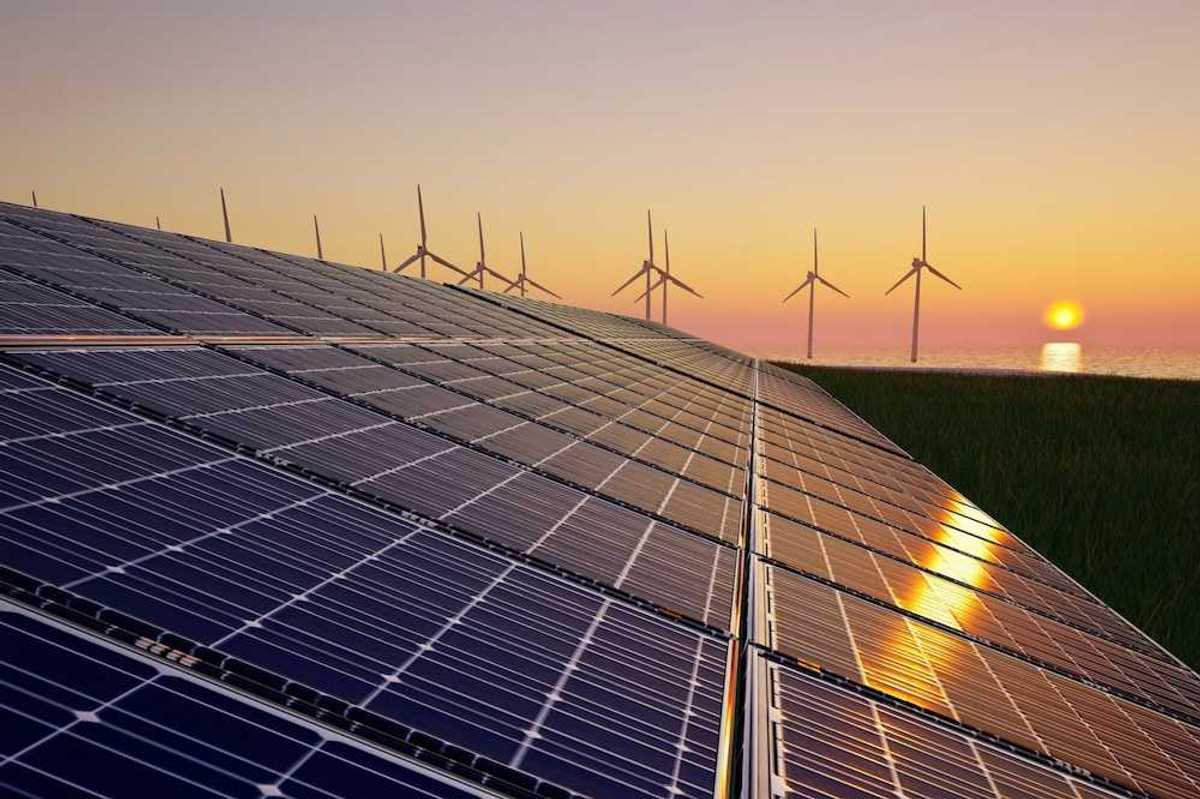 Solar panels with wind turbines in the background