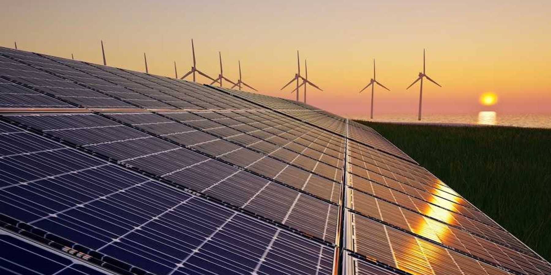 Solar panels with wind turbines in the background