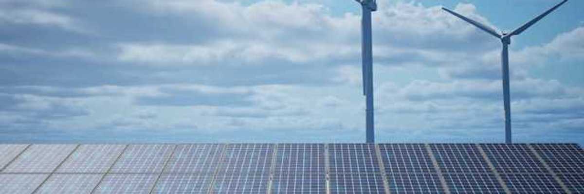 Solar panels with wind turbines in the background