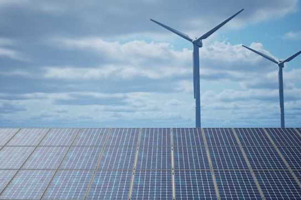 Solar panels with wind turbines in the background