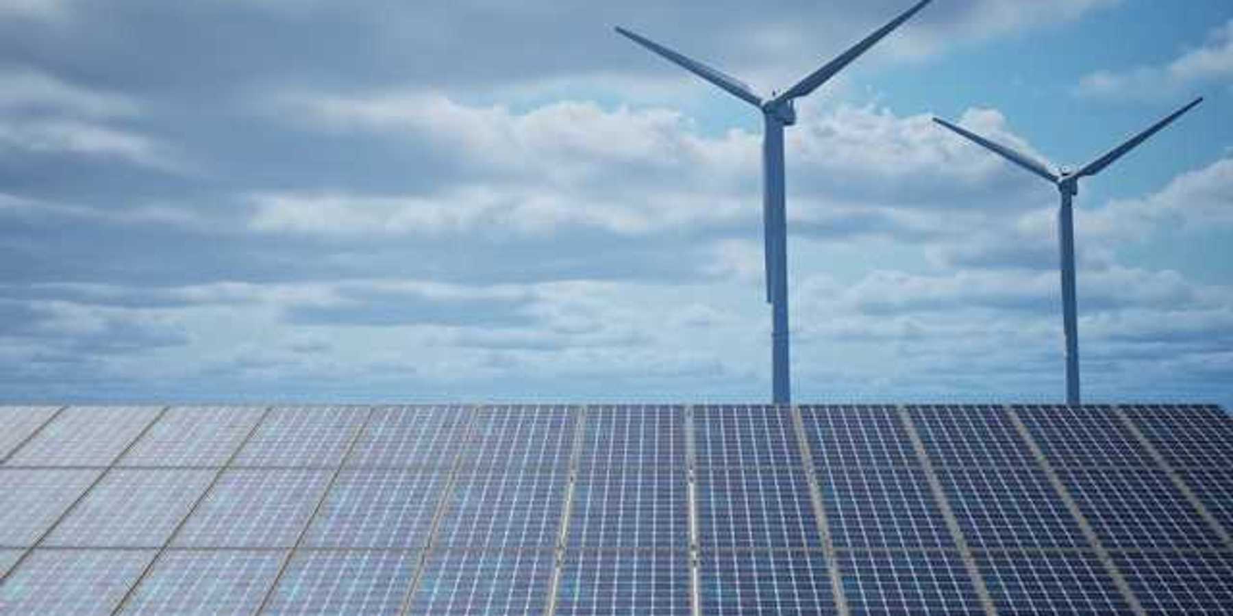 Solar panels with wind turbines in the background
