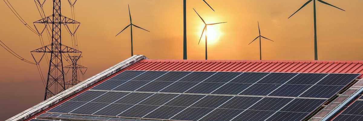 Solar power panels on a roof with wind turbines and powerlines behind