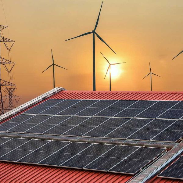 Solar power panels on a roof with wind turbines and powerlines behind