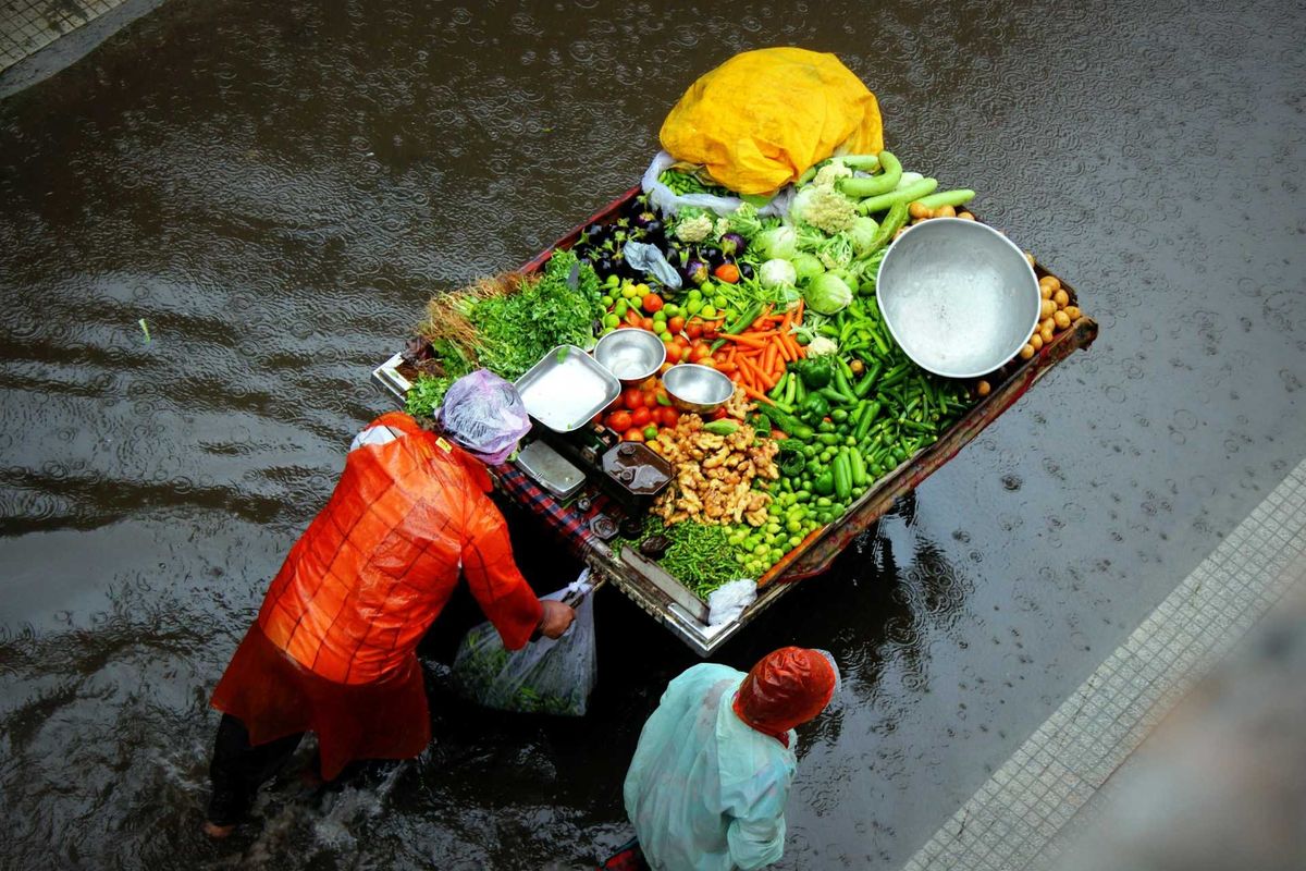Street vendors push food cart through floodwaters