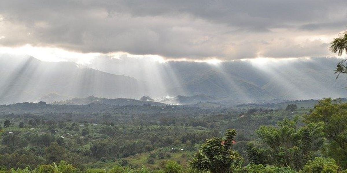 Sunlight filtering through clouds above a green landscape
