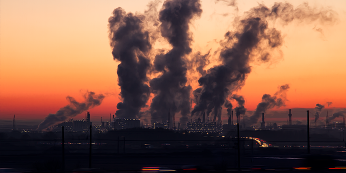 Sunset view of power plant emitting smoke