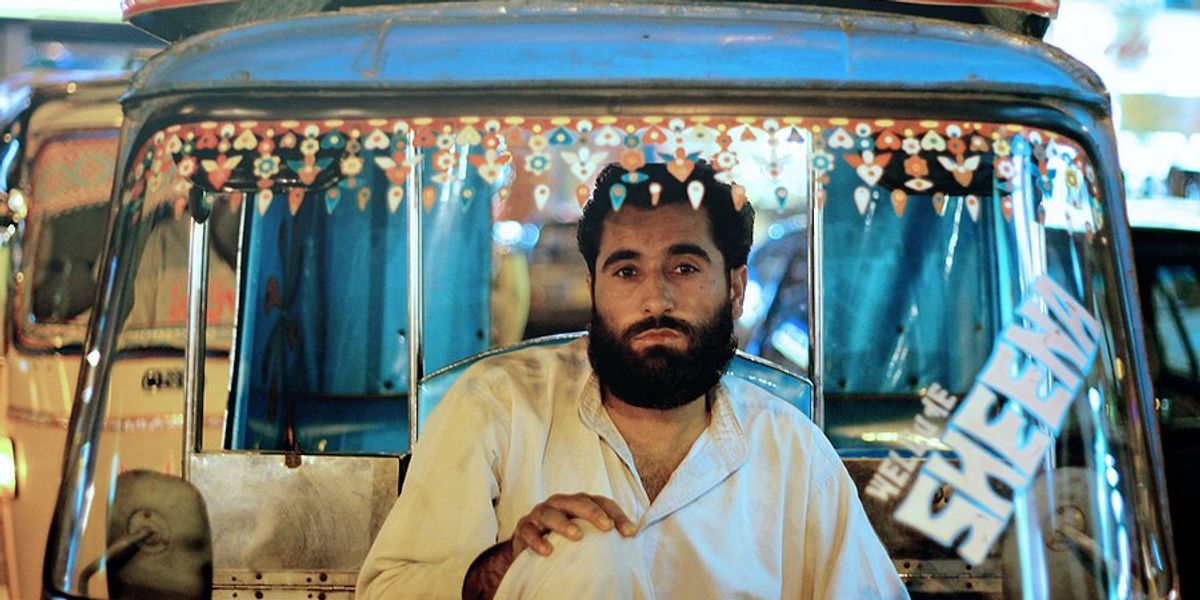 Taxi driver inside his car looking at the camera through the windshield in Karachi Pakistan.