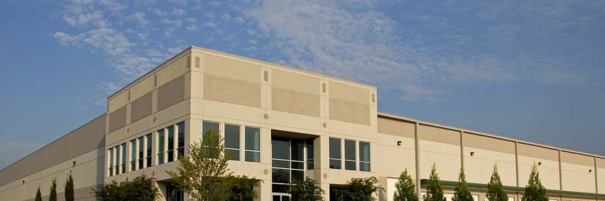 The exterior of a generic warehouse building with the blue sky in the background
