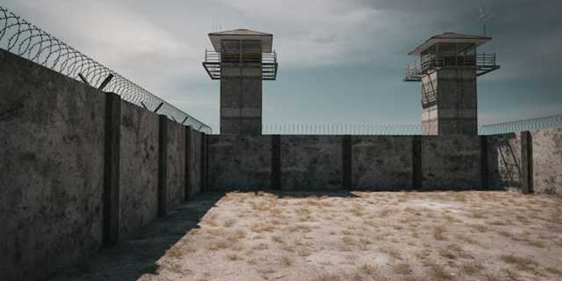 The exterior of a prison with prison towers and barbed wire