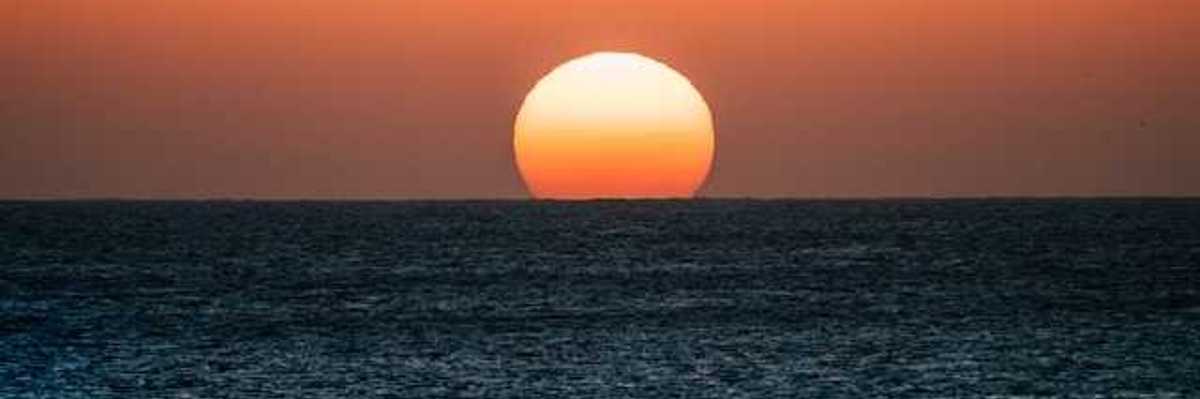 The ocean with the setting sun on the horizon
