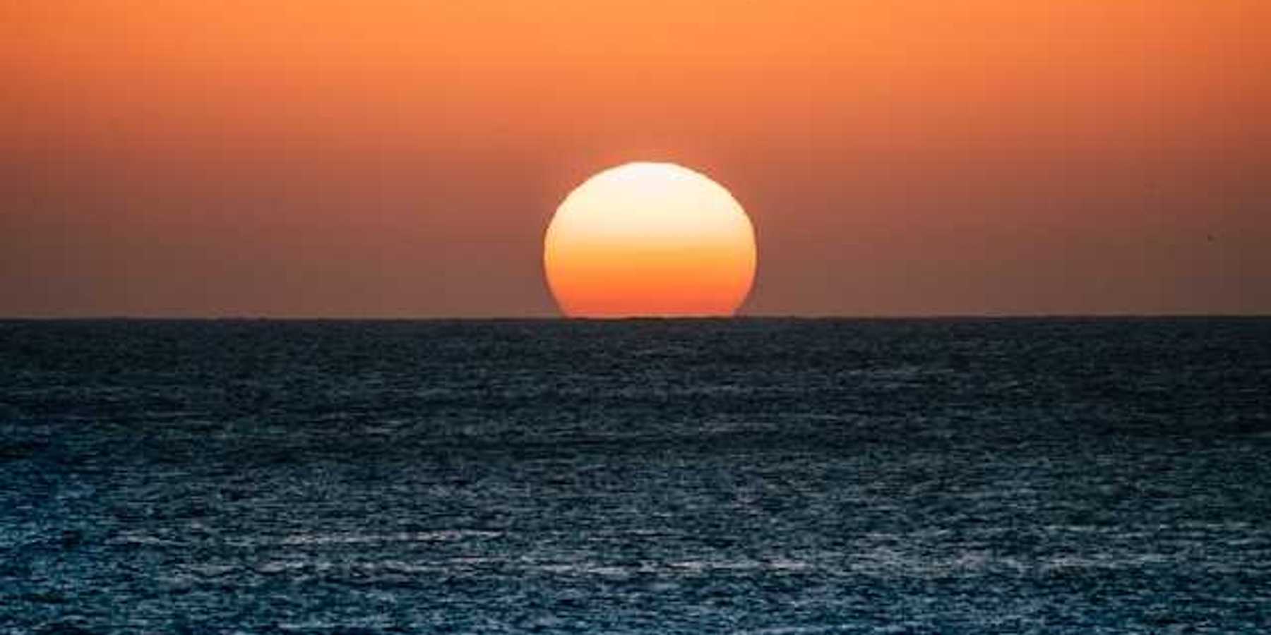 The ocean with the setting sun on the horizon