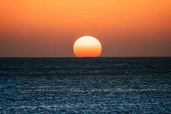 The ocean with the setting sun on the horizon