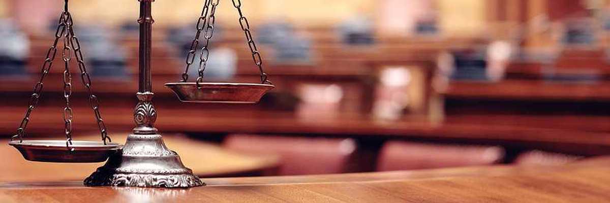 The scales of justice sitting on a desk with a courtroom in the background