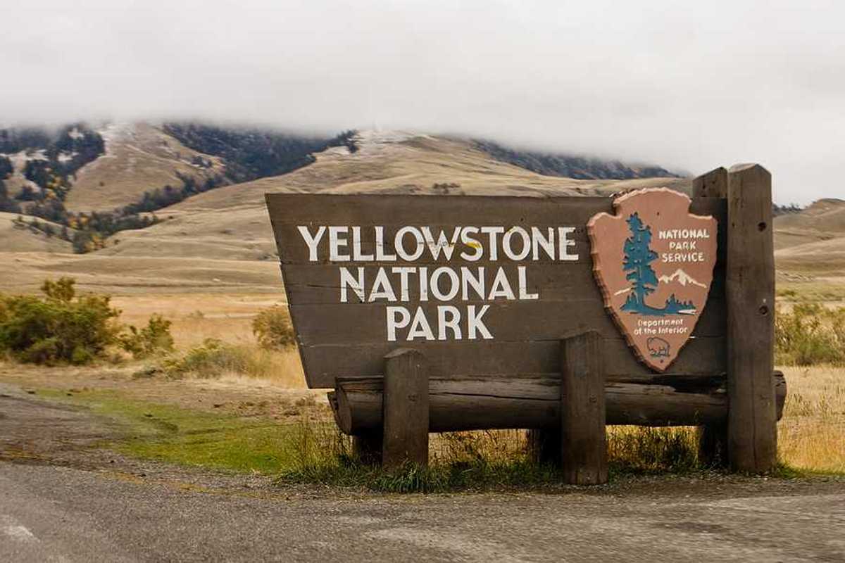 The sign upon entering Yellowstone National Park with hills int he background