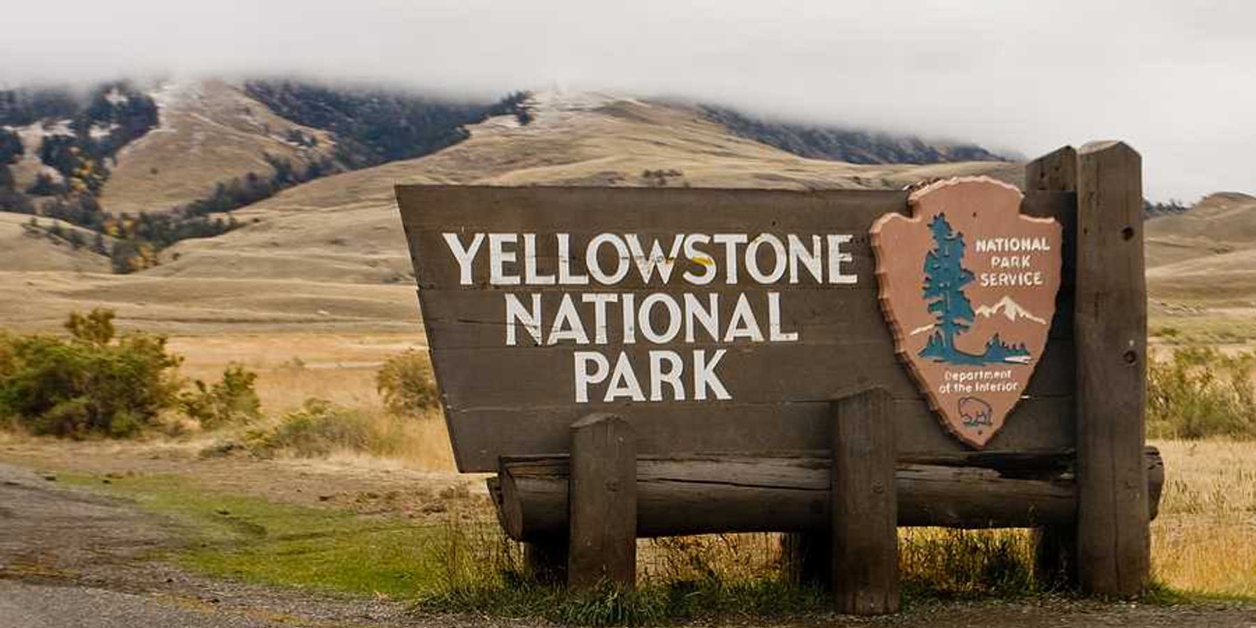 The sign upon entering Yellowstone National Park with hills int he background