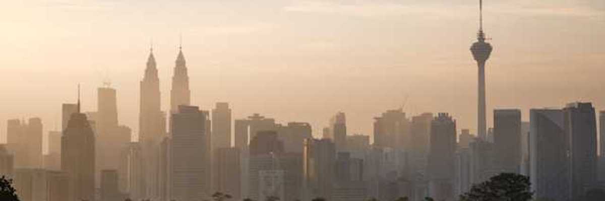 The skyline of Kuala Lumpur, Malaysia in the morning with trees in the foreground