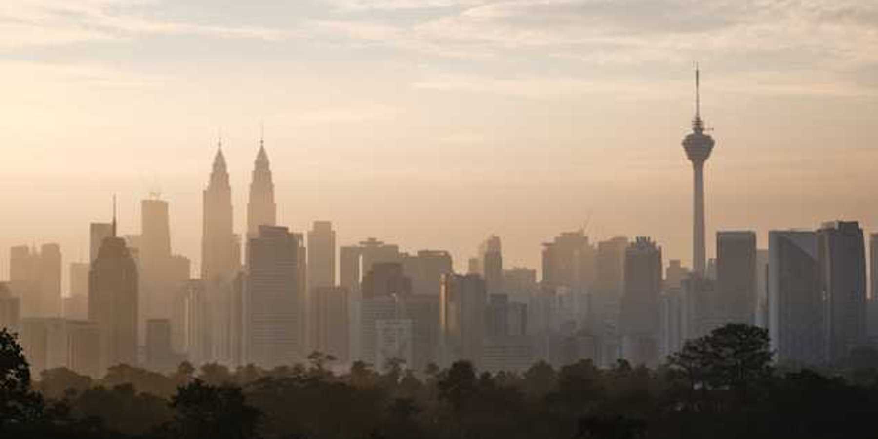 The skyline of Kuala Lumpur, Malaysia in the morning with trees in the foreground