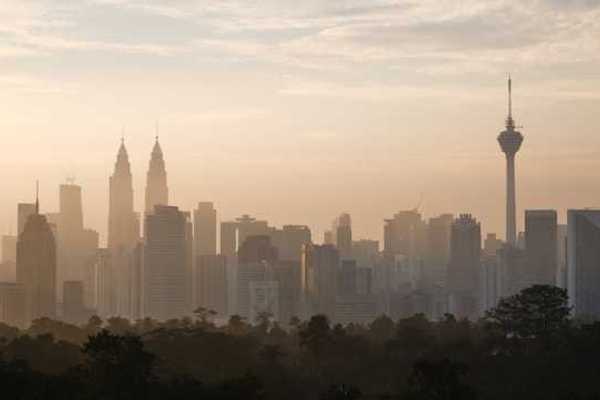 The skyline of Kuala Lumpur, Malaysia in the morning with trees in the foreground
