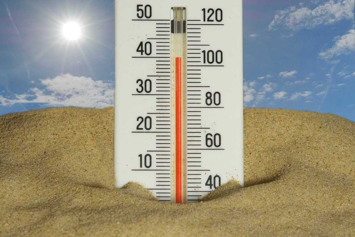 Thermometer stuck in the sand under a hot sun, reading 40 degrees C and 104 degrees F